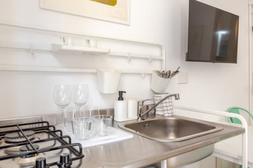 Moderna cucina in appartamento Art House Roma con piano cottura, lavello, bicchieri e ripiani a muro