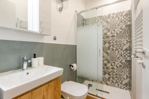 Bagno moderno dell'appartamento Art House Roma con piastrelle verdi, lavabo bianco, doccia decorata e WC