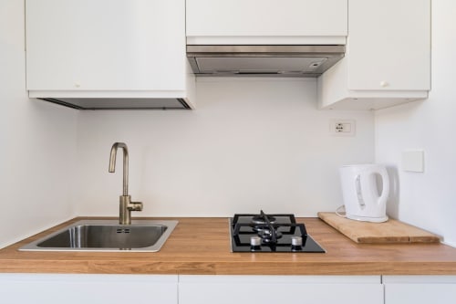 Cucina moderna in appartamento romano con piano in legno, lavello in acciaio inox, piano cottura a gas e cappe bianche