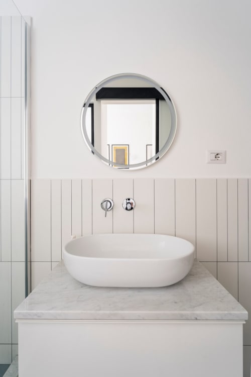 Moderno lavabo in ceramica bianca su piano marmo, specchio rotondo e rubinetto cromato presso Art House Rome