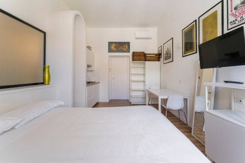 Camera da letto moderna in Art House a Roma con letto, scrivania, TV e arredi bianchi