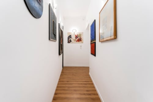 Corridoio nell'appartamento Art House Rome con quadri incorniciati su pareti bianche e pavimento in legno
