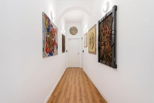 Corridoio dell'appartamento Art House Villa Borghese a Roma, con opere d'arte su pareti bianche e pavimenti in legno