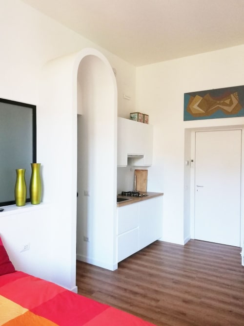 Cucina moderna di monolocale con mobili bianchi, piano di lavoro in legno e fornello a gas a Villa Borghese, Roma