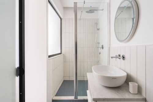 Moderno bagno di Art House Villa Borghese Roma con vasca freestanding, doccia walk-in, specchio rotondo e pareti in piastrelle bianche