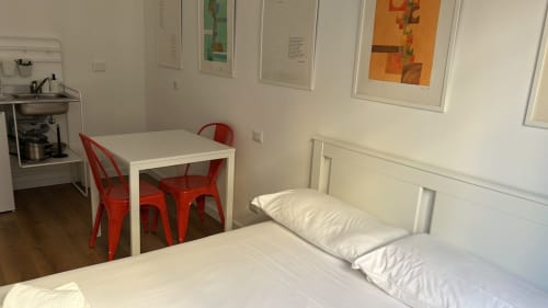 Camera da letto moderna nella Villa Torlonia Art House di Roma con letto bianco, sedie rosse, tavolo da pranzo e angolo cottura