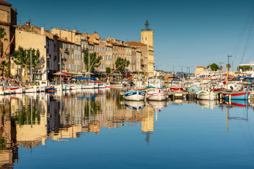 Port méditerranéen pittoresque avec bateaux colorés et bâtiments historiques en pierre jaune près de Colombes