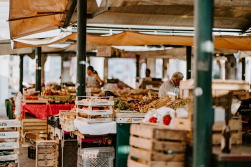 Étals de produits frais au marché fermier Locavilla à Colombes, avec auvents orange et caisses en bois de légumes et fruits