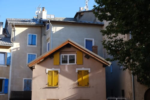 Façade de l'hôtel Locavilla à Colombes, France, avec ses volets jaunes charmants et portes bleues sur bâtiment beige