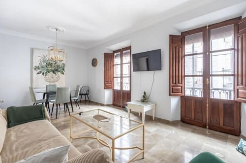 Suite del hotel CTH Granada con elegante sala de estar, comedor, puertas de madera y mobiliario moderno en Armilla