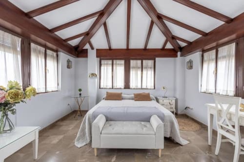 Habitación de lujo en CTH Granada con vigas de madera vista, cama queen, muebles blancos y vistas a Granada