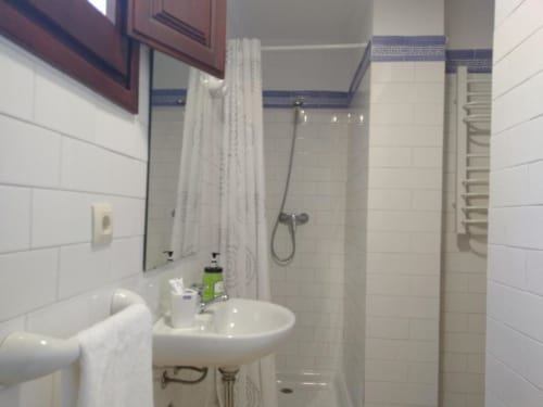 Baño moderno en apartamento CTH Granada con azulejos blancos, lavamanos, ducha, toallero y artículos de baño en Armilla