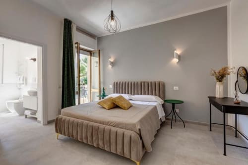 Modern suite bedroom at Palazzo Belvedere with plush bed, desk, ensuite bathroom, and balcony view in Chianciano Terme