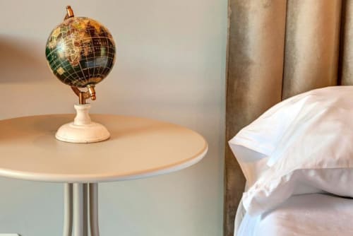 Decorative globe on round table beside bed in Palazzo Belvedere suite, Chianciano Terme