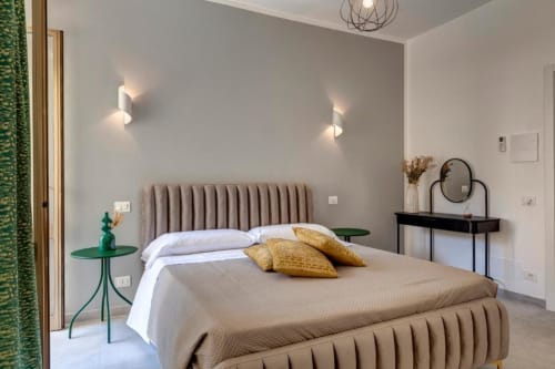 Modern suite bedroom at Palazzo Belvedere with upholstered bed, green accent table, and black vanity mirror