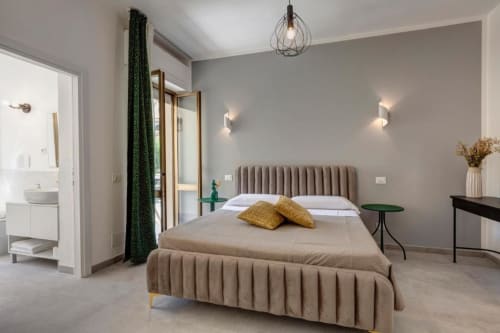 Modern suite bedroom at Palazzo Belvedere hotel in Chianciano Terme with taupe bed, yellow pillows, and ensuite bathroom