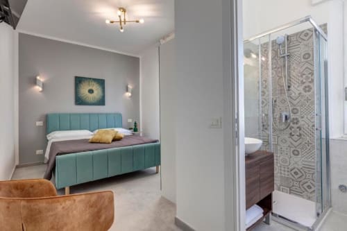Modern double bedroom at Palazzo Belvedere with turquoise bed, ensuite bathroom, and contemporary furnishings in Chianciano