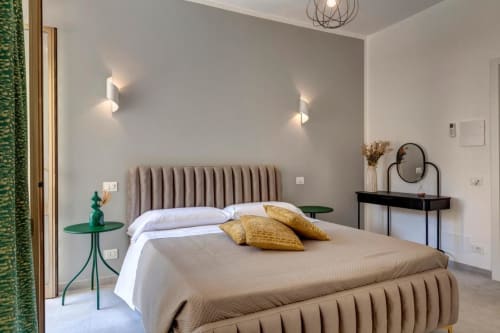 Modern bedroom at Palazzo Belvedere hotel in Chianciano Terme with upholstered headboard, golden pillows, and elegant