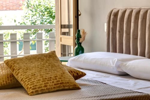 Bedroom at Palazzo Belvedere in Chianciano Terme with mustard pillows, white bedding, and garden view