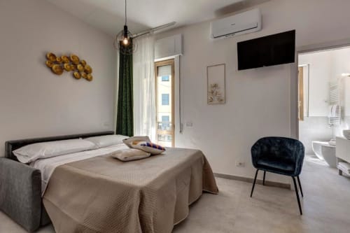 Modern suite at Palazzo Belvedere in Chianciano Terme with bed, balcony, TV, and dark accent chair