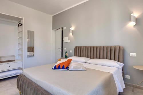 Modern double bedroom at Palazzo Belvedere with taupe upholstered headboard, white bedding, and contemporary furnishings in