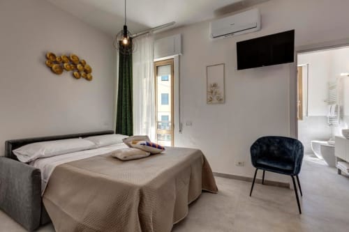 Modern bedroom at Palazzo Belvedere, Chianciano Terme with bed, dark armchair, wall art and balcony access
