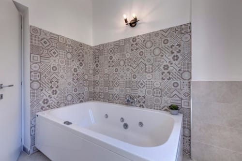 White jacuzzi bathtub with patterned tile surround in Palazzo Belvedere suite, Chianciano Terme