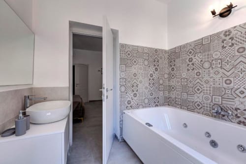 Modern bathroom with Jacuzzi tub and patterned tile walls at Palazzo Belvedere hotel suite, Chianciano Terme
