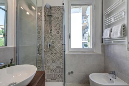 Modern bathroom at Palazzo Belvedere with walk-in shower, dual sinks, heated towel rack, and window overlooking Chianciano