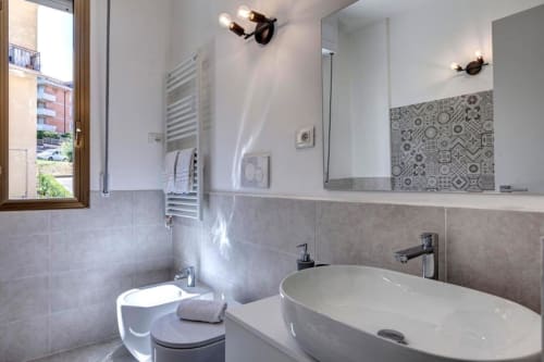 Modern bathroom at Palazzo Belvedere with oval sink, toilet, heated towel rack, and patterned tile accent wall