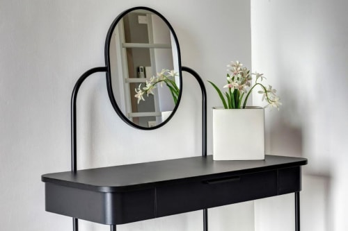 Black vanity desk with oval mirror and white orchid planter at Palazzo Belvedere, Chianciano Terme