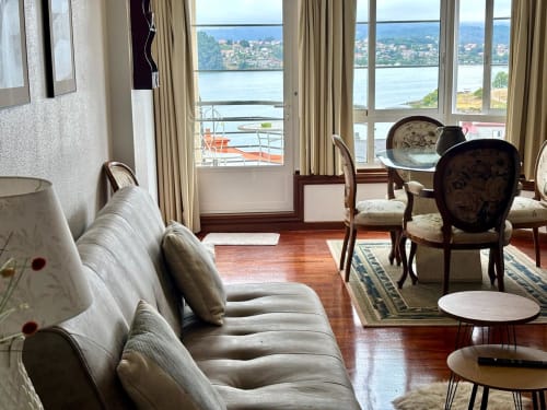 Elegante sala de estar con vistas al mar en Baiona, cómodos asientos y balcón frente al agua