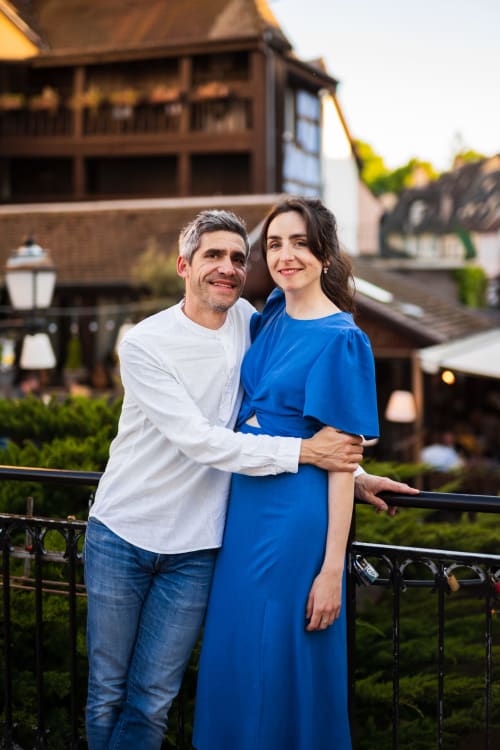 Couple smiling at Le JO·LIE Duplex hotel in Colmar with historic architecture backdrop