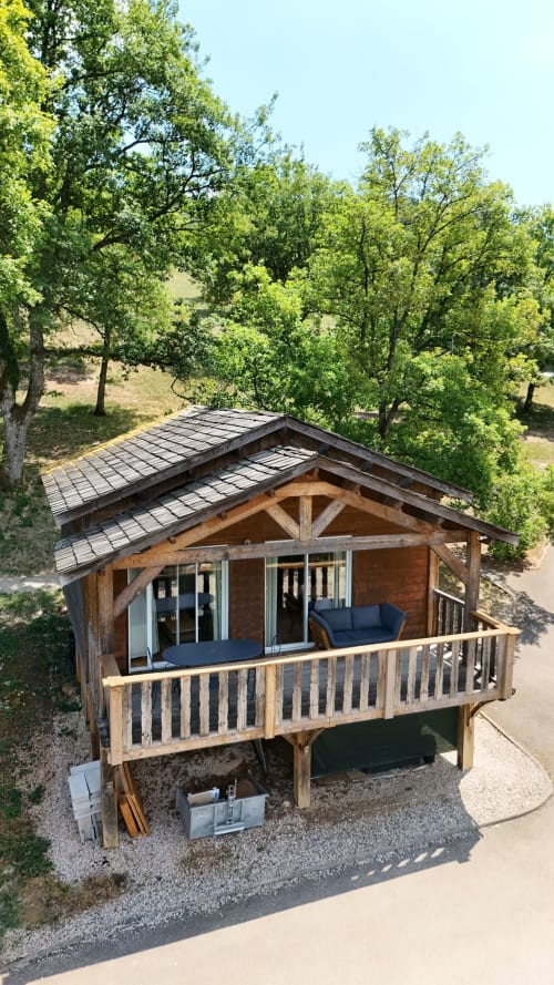 Moderno lodge in legno con terrazza coperta e spa alle Cabanes du Belvédère a Serrières-sur-Ain, circondato da verde rigoglioso