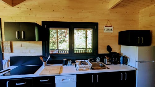 Cucina moderna nel Lodge LA BRUYERE con armadi neri, travi in legno e vista sulle montagne attraverso porte-finestre alle Cabanes du