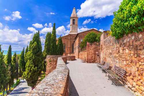 Historic cobblestone path with cypress trees, stone walls, and bell tower at Palazzo Belvedere in Chianciano Terme