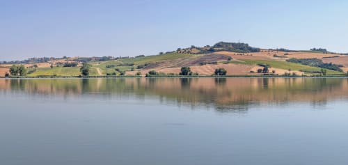 Serene lake view with rolling Tuscan hills and farmland reflecting in calm water near Chianciano Terme
