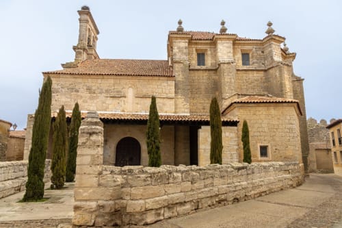 Iglesia de piedra histórica con cipreses en el centro medieval de Benavente, España