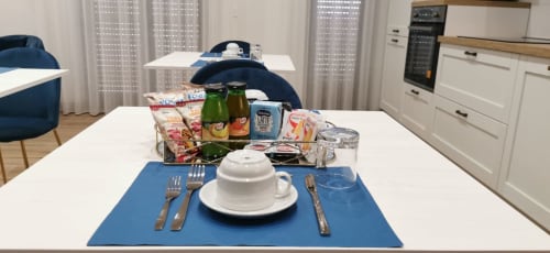 Moderna sala da pranzo di Ruah Pompei B&B con mise en place, bevande e sedie blu