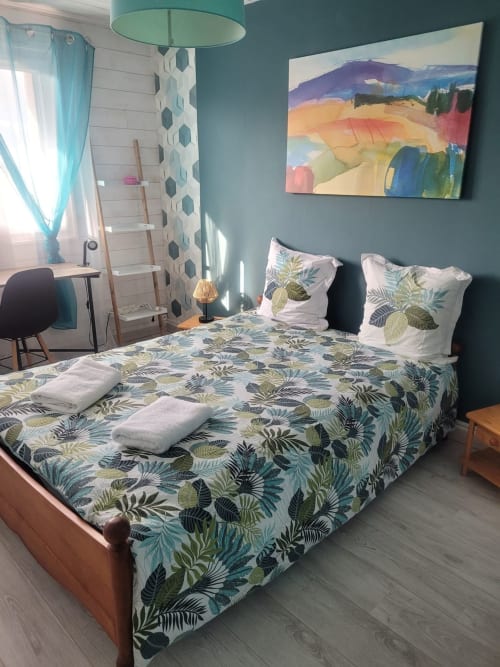 Chambre moderne à Val'Déco avec parure tropicale, murs bleu-canard, art paysager coloré et vue sur la ville aux Ponts de Cé