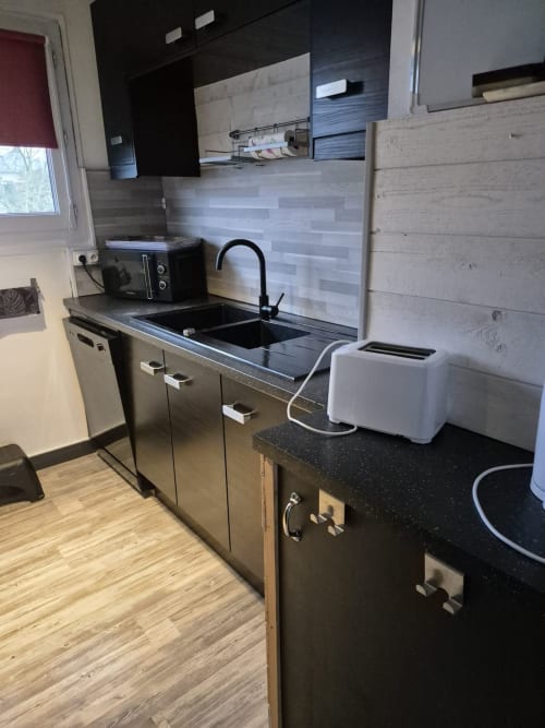 Cuisine moderne avec comptoirs, évier et électroménagers noirs de l'appartement Val'Déco, Les Ponts de Cé
