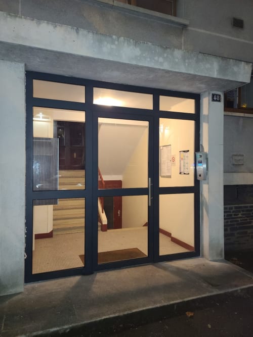 Porte d'entrée moderne en verre de l'appartement Val'Déco aux Ponts de Cé, vue intérieure illuminée