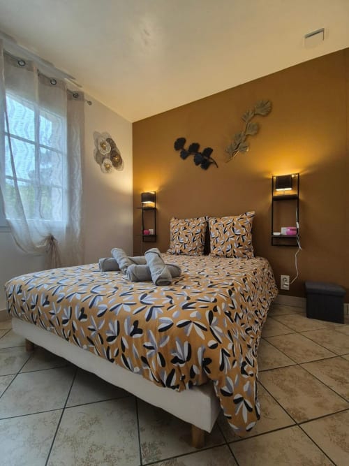Chambre moderne aux murs moutarde, literie à motifs et décoration murale à l'appartement Val'Déco Conciergerie aux Ponts de Cé
