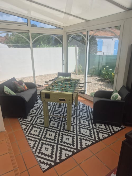 Véranda avec baby-foot, fauteuils noirs et vue sur le jardin à Val'Déco Conciergerie, Les Ponts de Cé