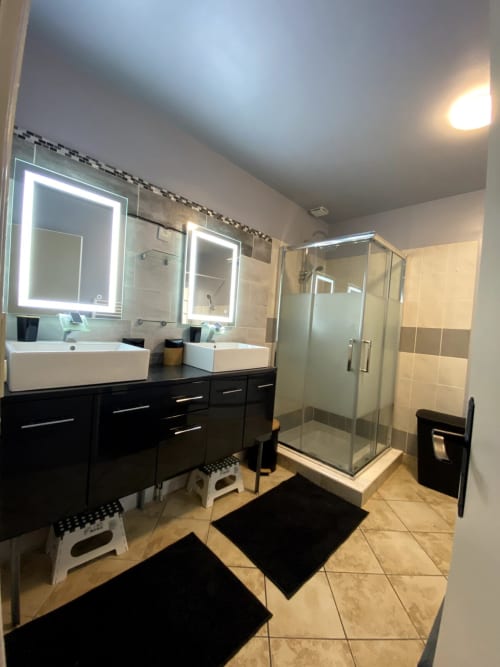 Salle de bain moderne de l'appartement Val'Déco avec double vasque, miroirs éclairés et douche vitrée aux Ponts de Cé