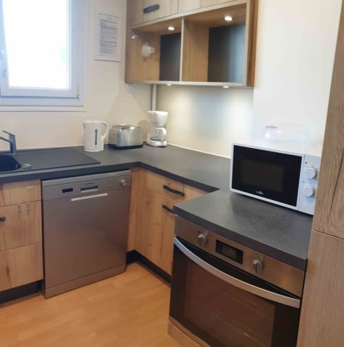 Cuisine moderne dans l'appartement Val'Déco aux Ponts de Cé, avec armoires en bois, comptoirs foncés et appareils inox