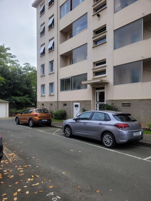 Zone de stationnement de la résidence Val'Déco Conciergerie aux Ponts de Cé avec deux véhicules et façade résidentielle