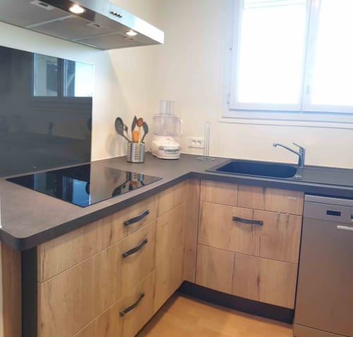 Cuisine moderne de l'appartement Val'Déco aux Ponts de Cé, avec meubles en bois, plan de travail foncé et cuisinière à induction