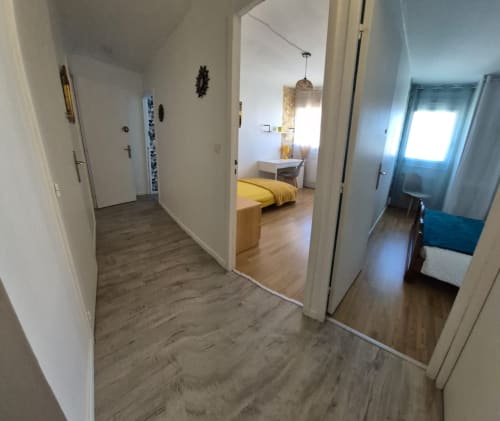 Couloir de l'appartement Val'Déco Conciergerie, Les Ponts de Cé, menant à une chambre avec literie jaune et plusieurs