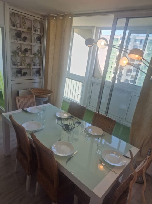 Espace de repas moderne dans l'appartement Val'Déco avec vue sur la ville, table dressée et luminaires contemporains